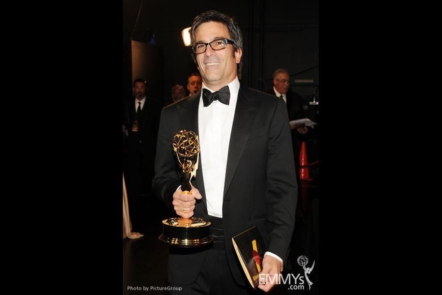 Mike Spiller Director Producer Cinematographer holds his Emmy award. Wearing a Black Tuxedo and a big smile